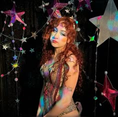 a woman with red hair and makeup is standing in front of some star shaped decorations