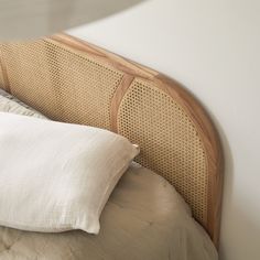 a close up of a bed with two pillows and a headboard made out of wicker