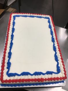 a square cake with red, white and blue frosting on a silver counter top