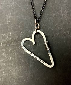 "This sweet-but-not-too-sweet heart necklace is all sterling silver. The pendant is made from stock materials: 12g. round wire for the heart, 20g. rivets, 18g. wrapped wire, 16g. Soldered jump rings connect the pendant to the 18\" long, rolo chain. Handmade T-bar clasp. The back of the pendant has been stamped: stelzer, sterling, handwrought, shown in last pic. The heart is about 1-5/8\" long and 1-2/16\" wide." Sterling Silver Heart Necklace Wire Wrapped, Heart-shaped Sterling Silver Soldered Necklace, Sterling Silver Heart-shaped Soldered Necklaces, Silver Heart Necklace, Hand Forged, Sterling Silver Heart-shaped Soldered Necklace, Hand Forged Silver Heart Necklace, Silver Hand Forged Heart Necklace, Sterling Silver Heart Necklace With Soldered Details, Small Heart Pendant