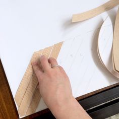 a person is working with wood and glue on a piece of white paper that has been cut out