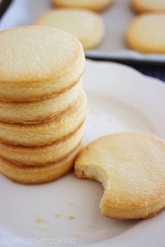 a stack of cookies sitting on top of a white plate next to other cookies in the background