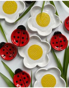 ladybugs and daisies are painted on ceramic dishes