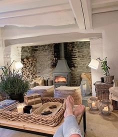 a person's feet resting on a coffee table in front of a fire place