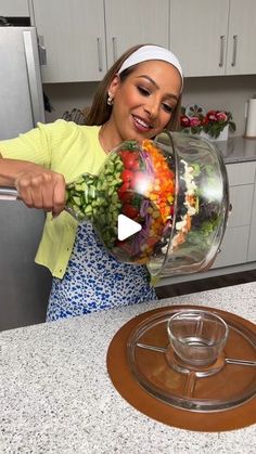 a woman is holding a bowl full of vegetables