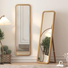 two mirrors sitting next to each other on top of a wooden floor in front of a white wall