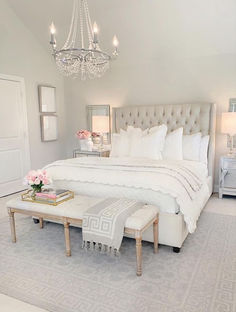 a bedroom with a large bed, chandelier and white furniture in the room