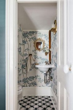 an open door leading to a bathroom with wallpapered walls and flooring in it