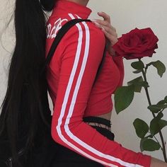 a woman with long black hair wearing a red jacket and holding a rose in her hand