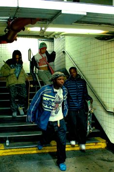 several young men are standing on the stairs with skateboards in their hands and one is holding his hand up