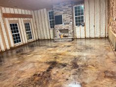 an empty room with stone fireplace and windows