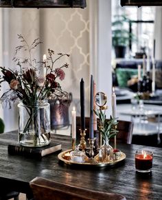 a dining room table with candles and flowers in vases on top of the table