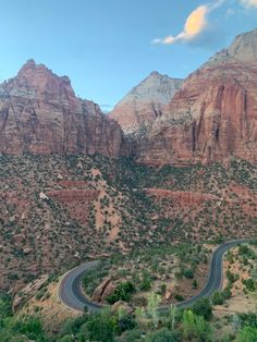 a winding road in the mountains with trees and bushes on both sides is surrounded by red rock formations