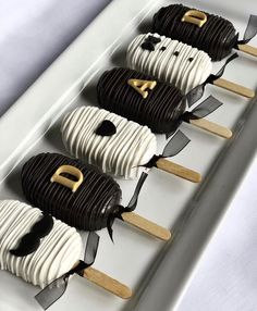 four desserts are arranged in the shape of panda faces on sticks with black and white icing