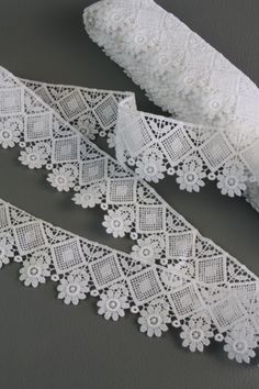 two pieces of white lace on a gray surface with one piece cut off and the other half rolled up