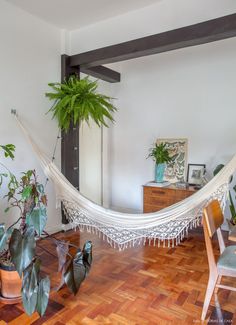 a hammock is hanging in the middle of a room with potted plants