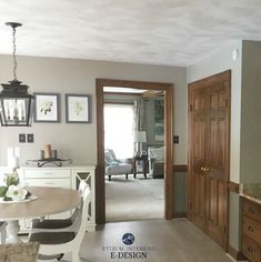 a living room and dining room area with wood doors, white chairs, and beige walls