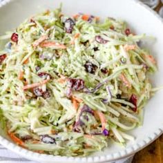 a white bowl filled with coleslaw and cranberries on top of a table