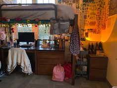 a dorm room with a desk and computer on top of it in front of a window