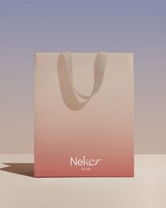 a pink and white shopping bag sitting on top of a table next to a wall