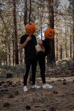 two people wearing pumpkin heads in the woods