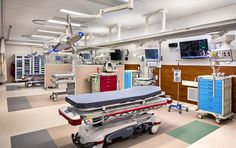 an empty hospital room with medical equipment on the floor and televisions hanging from the ceiling