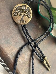 This awesome bolo tie has a round metal pendant with an engraved tree. Black leather adjustable cord. It is handmade in our shop.. Quality guaranteed, picture does not do this buckle justice! Pendant measures 1 1/4''   We have matching belt buckles to pair!