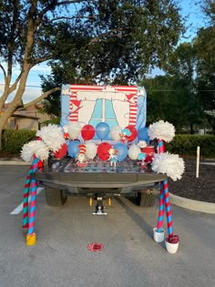 the back of a truck decorated with balloons and pom poms