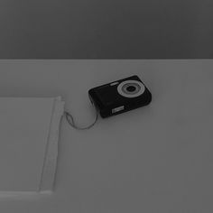 a black and white photo of a camera on the floor next to a piece of paper