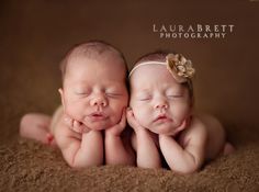 two newborn babies cuddle together in the middle of brown carpeted area with their eyes closed