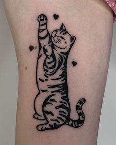 a black and white cat tattoo on the back of a woman's thigh,