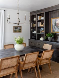 a dining room table with chairs and a vase filled with flowers on top of it