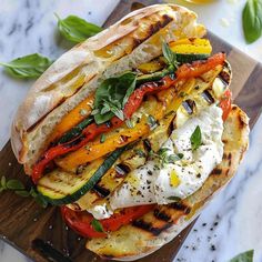 a grilled sandwich with vegetables and cheese on a cutting board