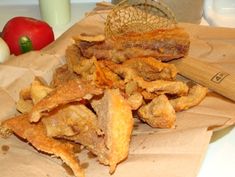 some fried food sitting on top of a brown paper bag next to an apple and knife