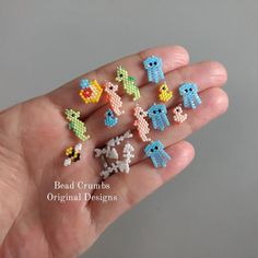 a hand is holding six small pixelated items in it's palm, with the text bead crumbs original designs