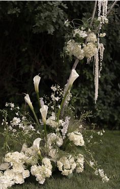 white flowers and greenery are arranged in the grass