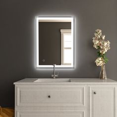 a bathroom vanity with a large mirror above it and flowers in the vase on top