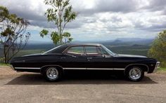 an old black car parked on top of a hill