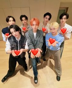 group of young men holding red hearts in front of their faces and posing for the camera