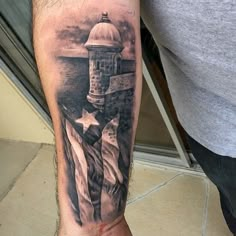 a man's arm with an american flag and lighthouse tattoo on it