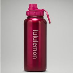 a red water bottle with the name millennium on it and a pink lid is sitting in front of a gray background