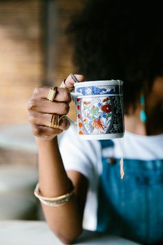 a woman holding up a coffee cup with designs on it