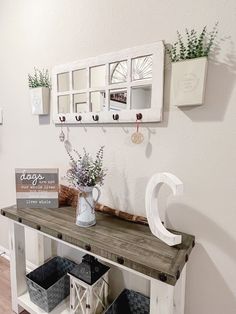 a white shelf with some flowers on top of it and two baskets under the shelf