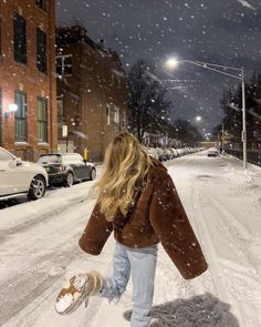 a woman walking down a snow covered street with her foot in the air while it's snowing