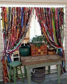 a table with two stools in front of a window covered by colorful curtain panels