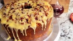 a bundt cake with icing and pecans on top sitting on a plate