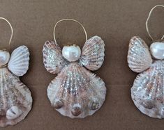 three seashells with pearls on them are sitting next to each other in the shape of angel wings