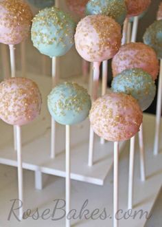 cake pops with sprinkles and blue frosting are on a white stand