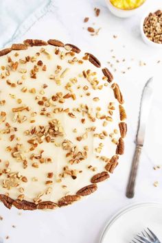 a pie with white frosting and pecans on top next to other desserts