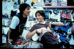 two young men standing next to each other in front of a store display filled with clothes